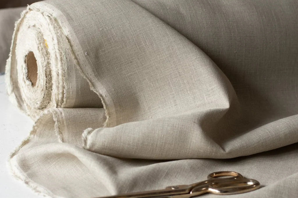 Rolled linen fabric with a pair of scissors on a light background