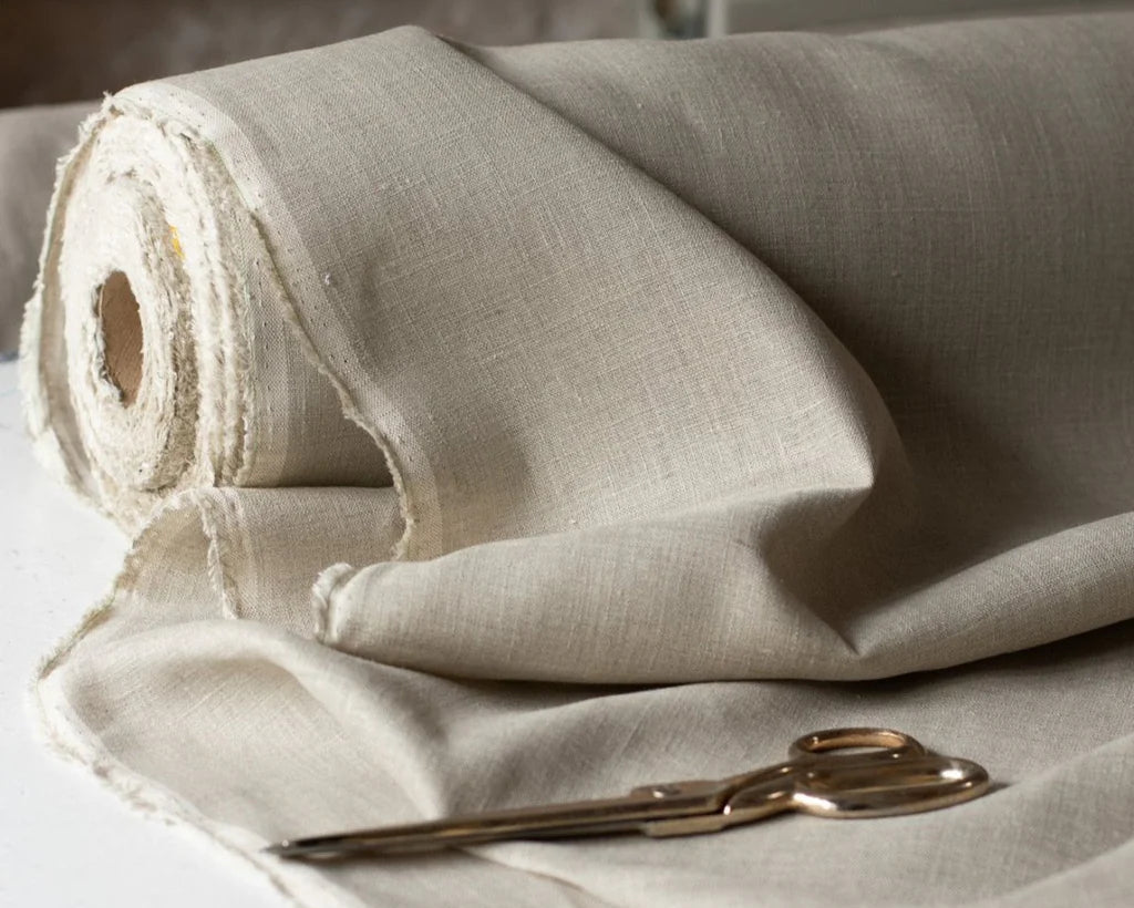 Rolled linen fabric with a pair of scissors on a light background