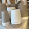 A collection of natural linen lamp shades displayed, showing a range of sizes from small to large with a two-tone color design.